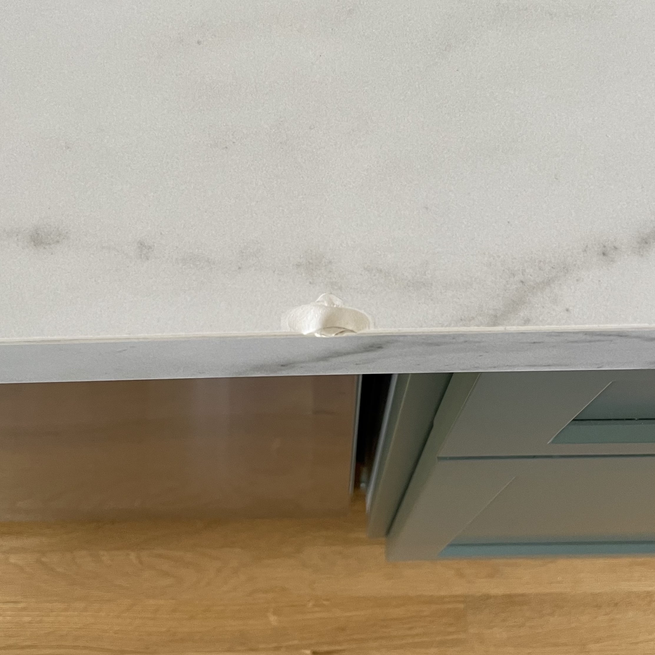 Old filler sitting proud on a chipped quartz countertop edge before repair